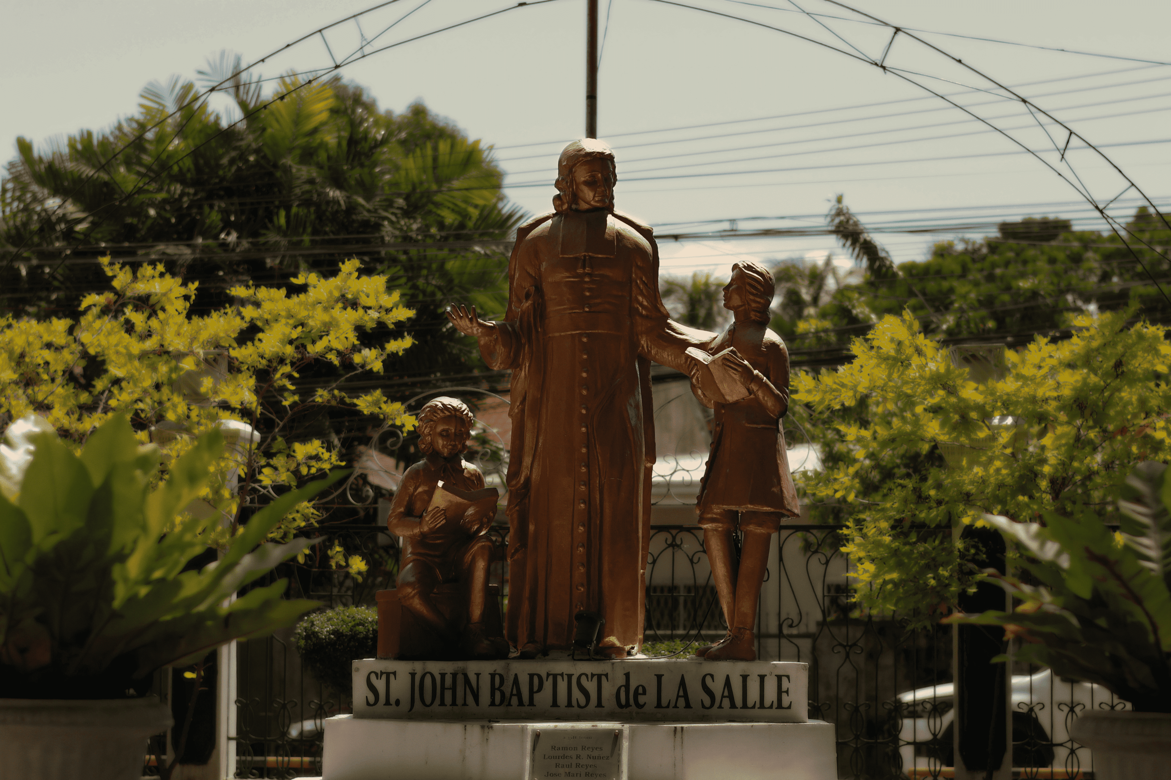 A bronze statue framed by yellow flowers