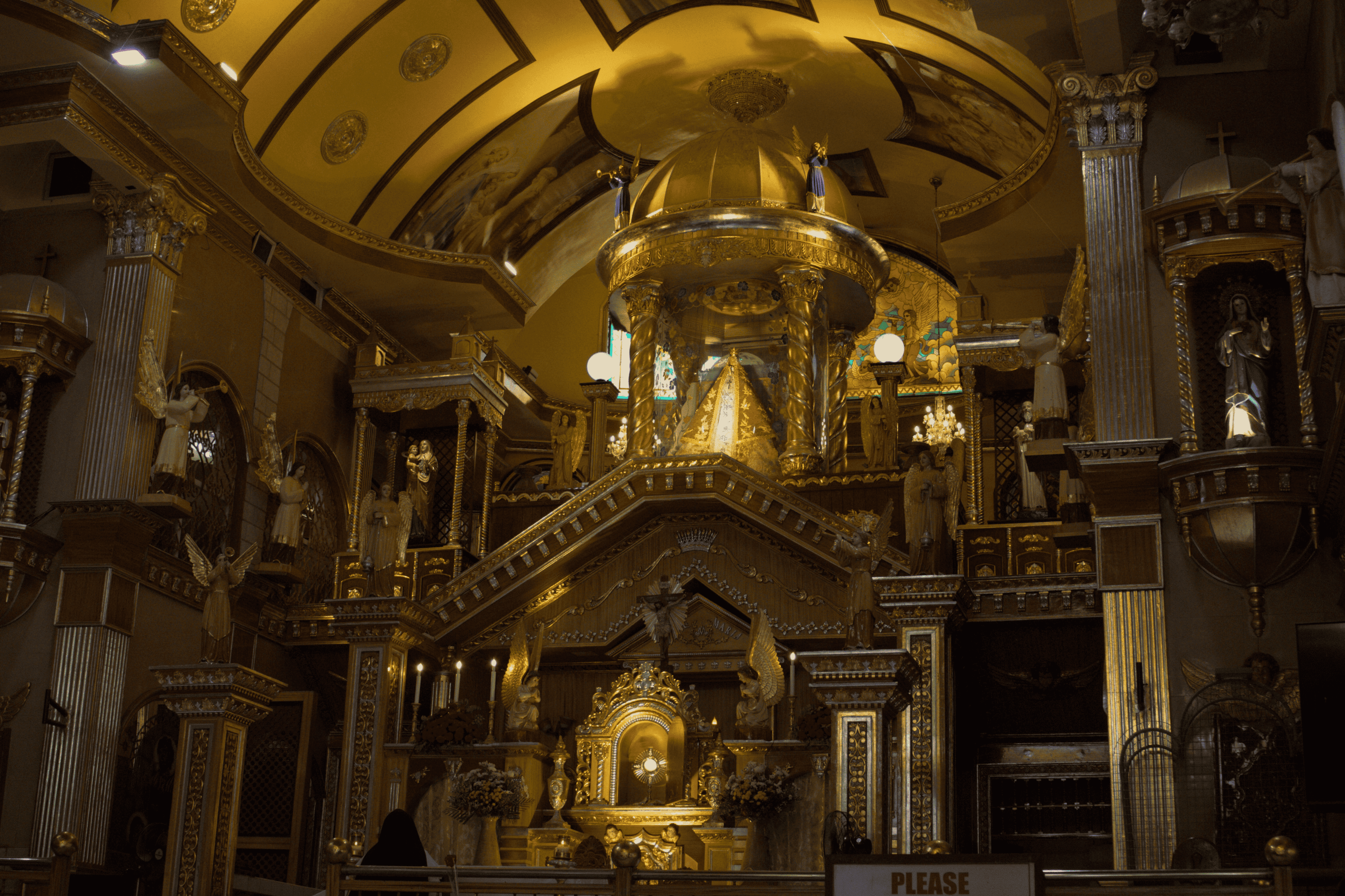 A golden church altar surrounded by statues and ornate columns