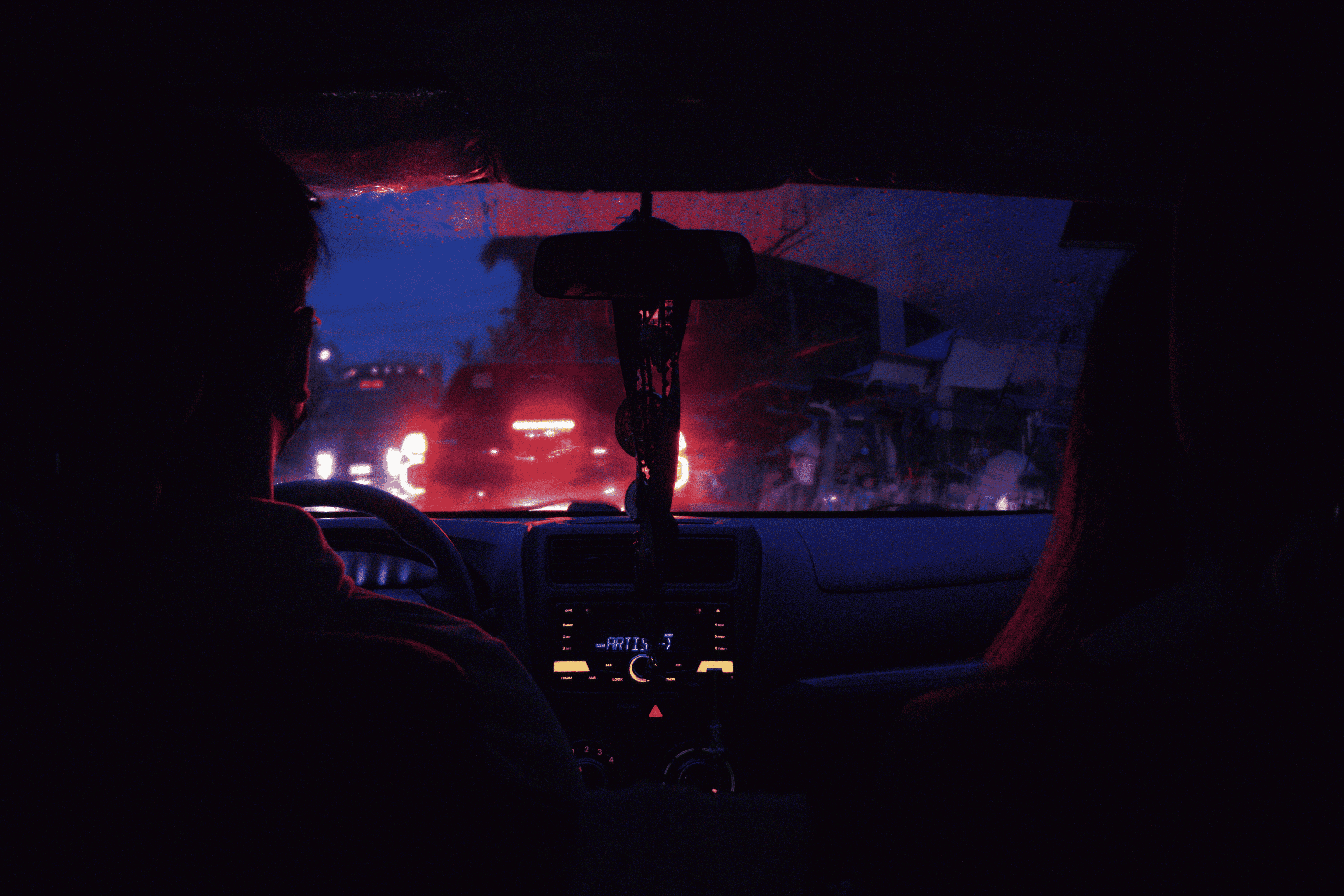 Brake lights through a rain-covered windshield at dusk