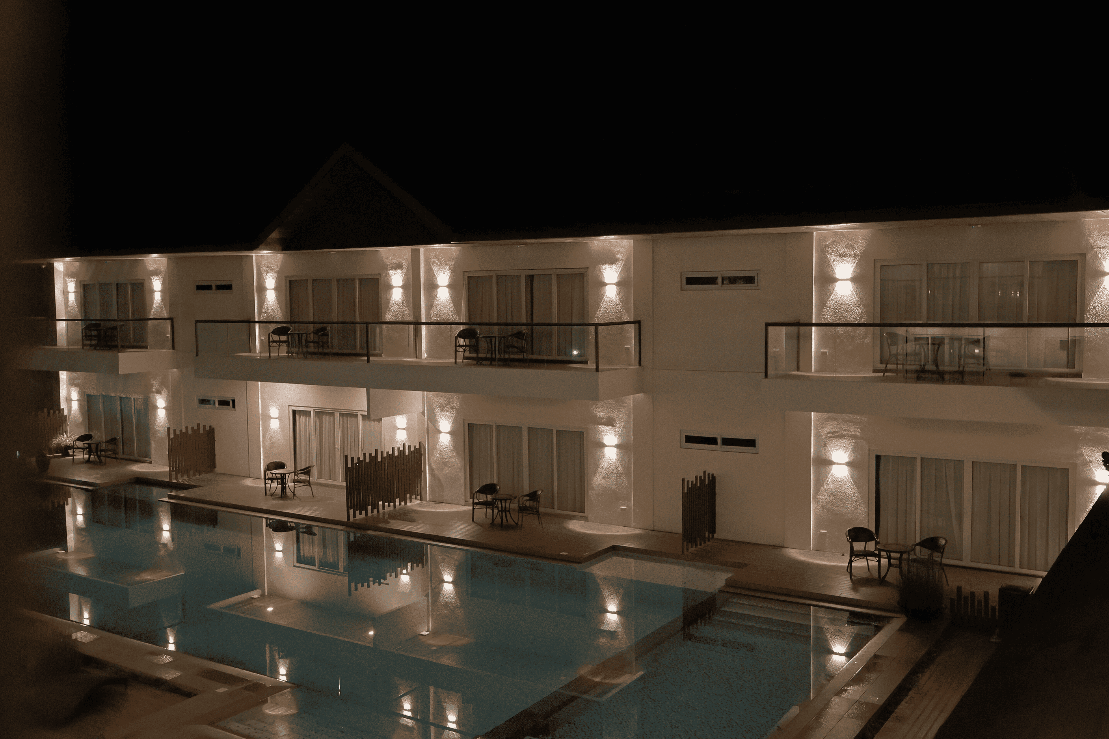 Lit balconies reflected in a swimming pool at night
